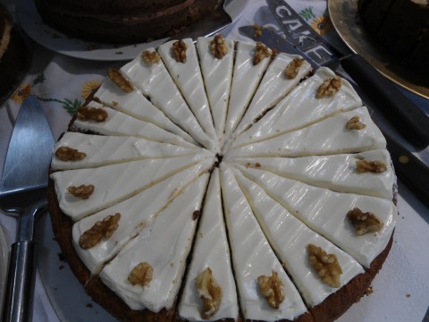 Close up of iced carrot cake, decorated with walnuts and sliced ready to serve. About twenty slices, I'd say. It was delicious.