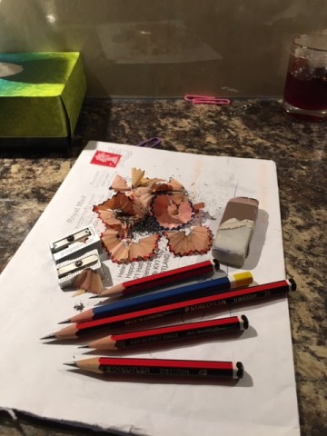 Full colour photo of five pencils on an envelop with a rubber, two pencil sharpeners and a lot of pencil shavings. The pencils look pretty short but extraordinarily sharp.